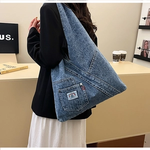 Detail view of washed denim tote bag with rainbow patch on a shoulder-carried model