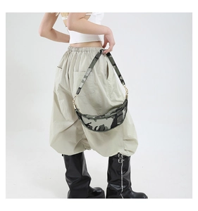 Detailed view of camouflage dumpling bag worn by model with adjustable shoulder strap
