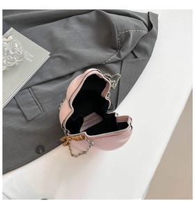 Detail view of pink heart-shaped bag with metal chain strap and woven zipper pull