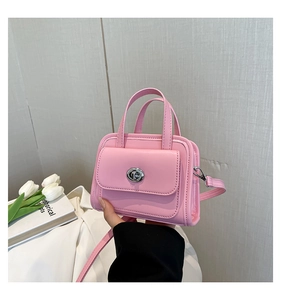 Detail of light pink PU leather handbag featuring silver metal turn-lock and dual handles