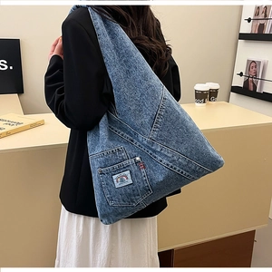 Detail view of denim hobo bag featuring utility pocket and stylish rainbow patch logo
