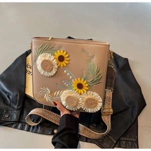Detailed close-up of pastoral embroidery with sunflower and daisy on crossbody bag