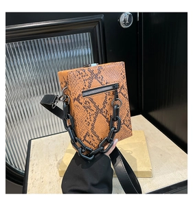 Detail of faux snake skin handbag with chunky black chain strap and metal zipper