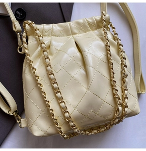 Detail of cream quilted leather bag with gold chain strap and drawstring closure