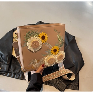 Detail of 3D floral embroidery and ethnic patterned strap on a brown shoulder bag