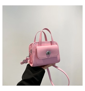 Close-up of pink handbag with silver metal rotary lock and adjustable shoulder strap