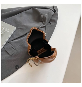 Macro view of brown gourd-shaped crossbody bag with polished leather and metallic chain