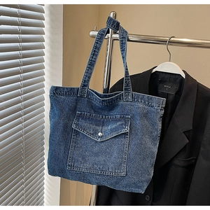 Detail of vintage denim tote bag showing texture, front pocket and metal button