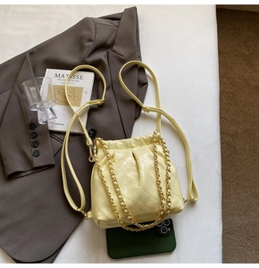 Detail view of yellow quilted drawstring backpack with gold chain and soft PU leather texture