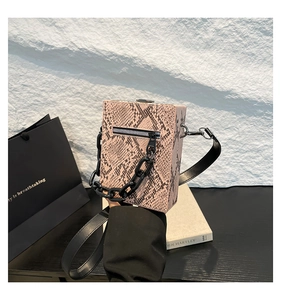Detail of snake print box bag with black resin chain and textured faux python finish