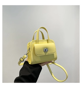 Detailed close-up of yellow leather handbag showing turn-lock closure and texture