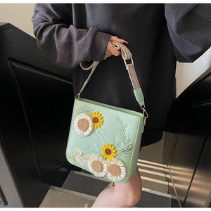 Detailed close-up of light green shoulder bag with sunflower and daisy floral embroidery