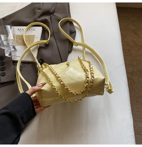 Detail of light beige quilted chain bag with gold metal handle on a stylish suit