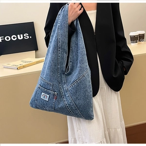 Close-up of vintage washed denim hobo bag with decorative rainbow patch on the side pocket