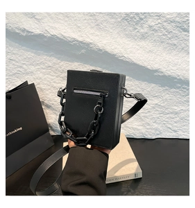 Close-up of black Saffiano leather box bag with silver zipper and chain handle detail