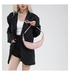 Close-up of pink crescent leather shoulder bag with gold metal hardware on female model