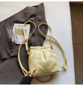 Detail view of light yellow quilted backpack with fine leather texture and chain strap