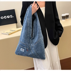 Macro shot of large washed blue denim shoulder bag with a colorful rainbow pocket detail