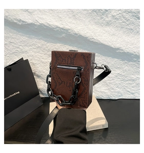 Close-up of brown snake print box crossbody bag with chunky black chain and metal zipper