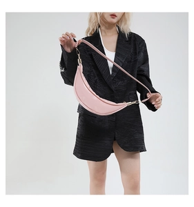 Detail view of pink crescent moon shoulder bag on a model wearing a black textured blazer