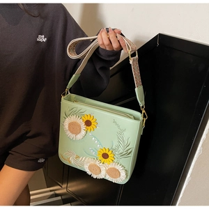 Detail of light green floral embroidery with sunflower on the crossbody bag strap