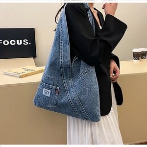 Detail of vintage washed denim tote bag with rainbow patch and external snap pocket