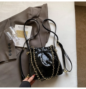 Detailed view of the black quilted drawstring bucket bag with elegant gold chain strap