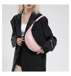 Model wearing pink crescent crossbody bag with glossy PU leather and gold zipper