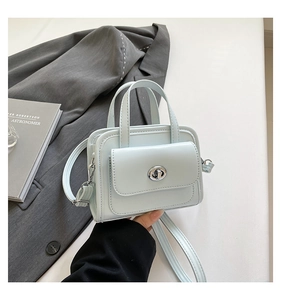 Close-up of minimalist mint green leather handbag with silver metallic turn-lock closure