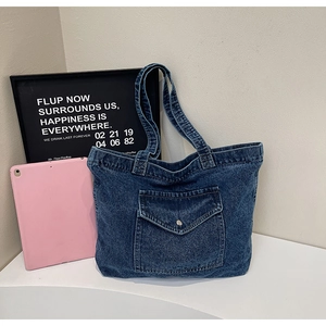 Close-up of vintage blue denim tote bag featuring an outer pocket with a metal buckle