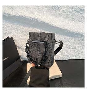 Detail of grey snake pattern crossbody bag featuring a thick black resin chain handle