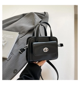 Detail of black mini briefcase with turn-lock closure and detachable shoulder strap