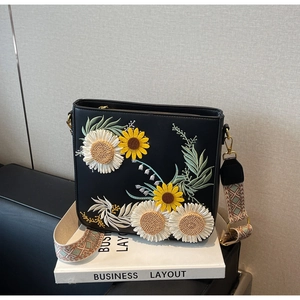 Detail of floral embroidery and ethnic jacquard strap on black shoulder bag