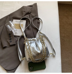 Detail view of silver quilted bucket bag with chain strap and elegant metallic texture