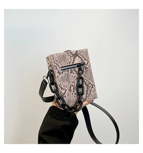 Detail of pink faux snakeskin crossbody bag with bold black chain and strap