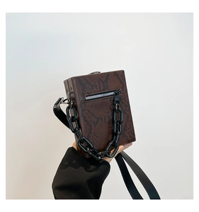 Close-up of brown snake texture square crossbody bag with black plastic chain detail