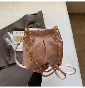 Detail of light pink quilted leather bucket bag with gold chain and drawstring