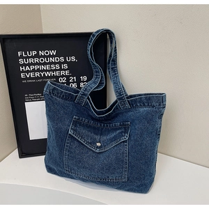 Detailed close-up of blue denim tote bag with front pocket and metal snap button