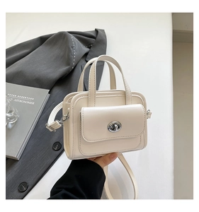 Detail of off-white mini briefcase bag with silver turn-lock and adjustable shoulder strap