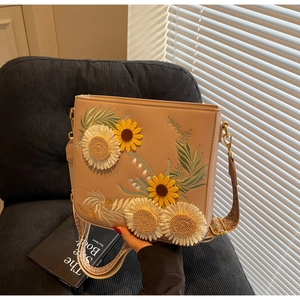Detail of embroidered sunflower and daisy motifs on a leather crossbody bag