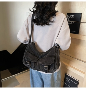 Detailed view of grey washed denim motorcycle bag with double front buckle pockets