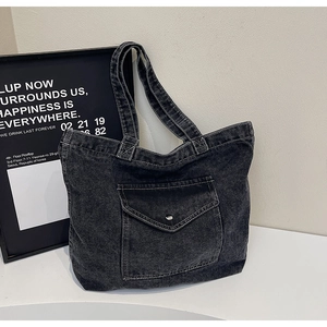 Detail of vintage washed denim tote bag with silver button front pocket and strap