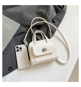 Close-up of a white leather handbag with a metal turn-lock clasp on a grey blazer