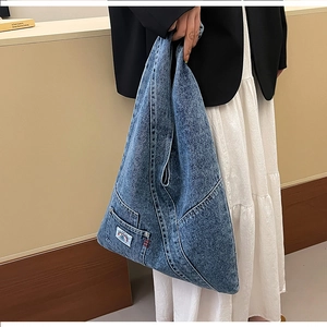 Detail of vintage washed blue denim tote bag with functional pockets and stitching