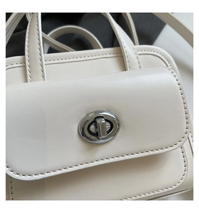 Close-up of cream white PU leather handbag featuring elegant silver metal turn-lock closure