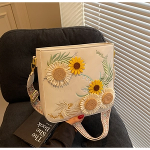 Close-up of white crossbody bag with sunflower embroidery and floral woven strap