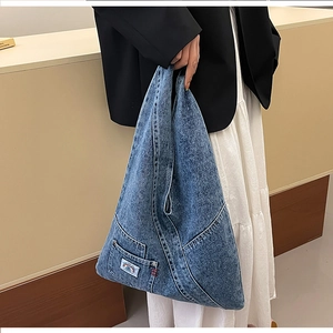Detail of vintage blue denim triangle bag featuring large capacity and brand patch pocket