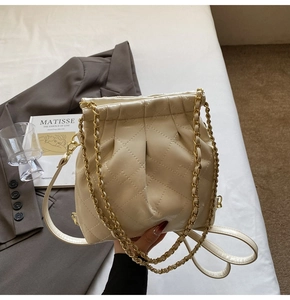 Detail view of cream quilted bucket bag with gold chain and drawstring closure