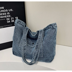 Detail of vintage blue denim tote bag featuring front flap pocket and sturdy shoulder straps