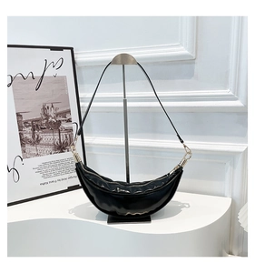 Detailed view of black crescent hobo bag with light gold zippers and leather strap